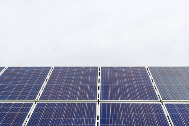 Paneles fotovoltaicos de células solares en planta de producción de energía con cielo azul nublado en el fondo
 - Foto, Imagen