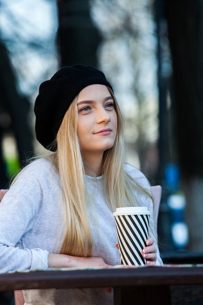 Gorgeous young woman with cup of coffee in city street. Coffee break. Coffee to go.Stylish hipster girl drinking coffee in street. - Foto, Bild