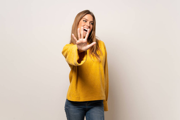 Frau mit gelbem Pullover über isolierter Wand, die mit den Fingern fünf zählt - Foto, Bild