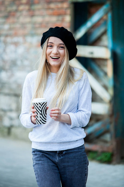 Prachtige jonge vrouw met kopje koffie in de stad straat. Koffiepauze. Koffie te gaan. Stijlvolle hipster meisje drinken koffie in de straat. - Foto, afbeelding