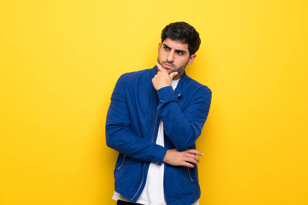 Uomo con giacca blu sopra il muro giallo pensando
 - Foto, immagini