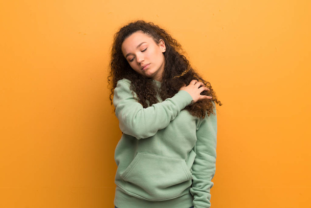 Adolescente sur un mur ocre souffrant de douleur à l'épaule pour avoir fait un effort
 - Photo, image
