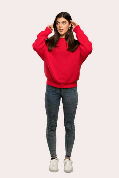 疑問を持つと孤立した背景を考えて赤のセーターとティーンエイ ジャーの女の子のフルレングス ショット - 写真・画像