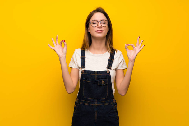 Woman over yellow wall in zen pose - Photo, Image