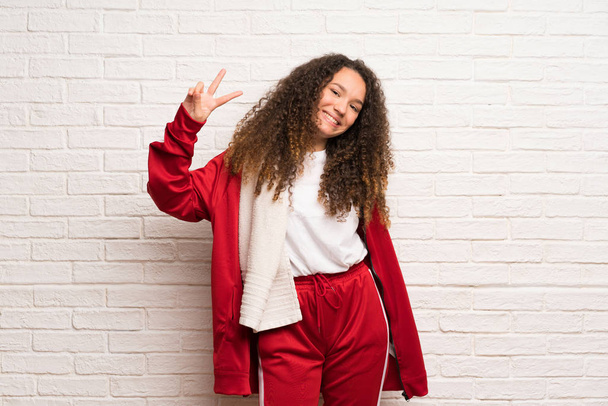 Teenager sport girl with curly hair smiling and showing victory sign - Photo, Image