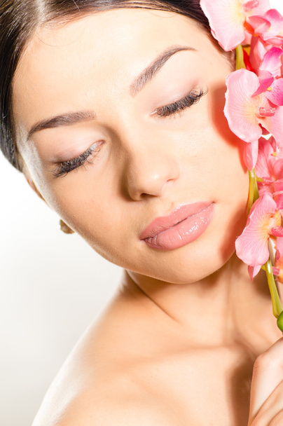 mooi meisje gezicht met de ogen gesloten & roze bloemen, perfecte huid en lippen op wit - Foto, afbeelding