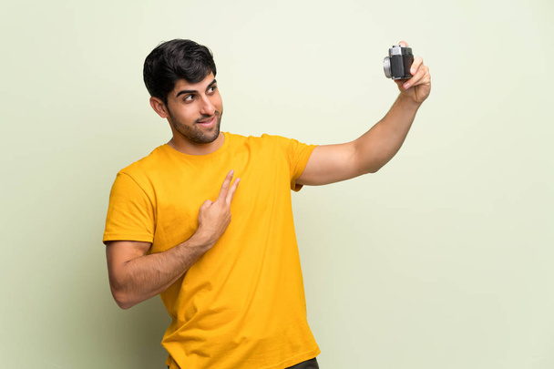Jonge man over roze muur een camera - Foto, afbeelding