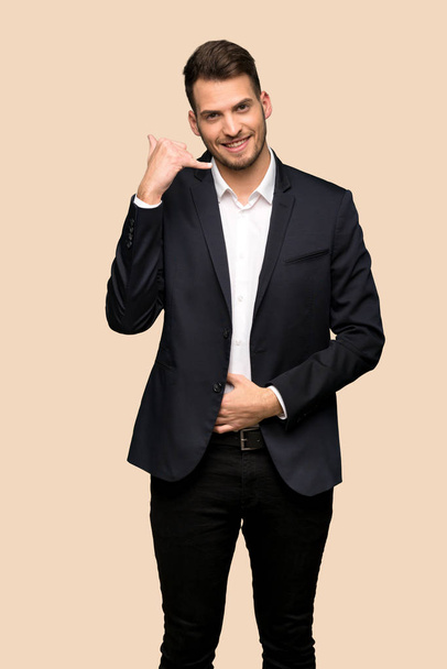 Handsome business man making phone gesture. Call me back sign over ocher background - Photo, Image
