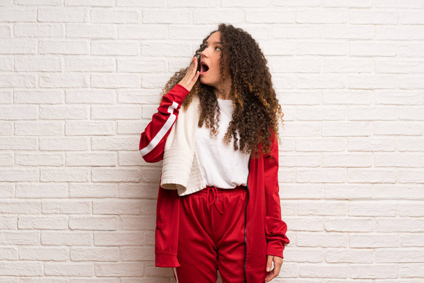Teenager sport girl with curly hair yawning and covering wide open mouth with hand - Photo, image