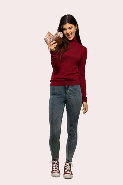 Un full-length shot di una ragazza adolescente con dolcevita in possesso di un portafoglio su sfondo isolato
 - Foto, immagini