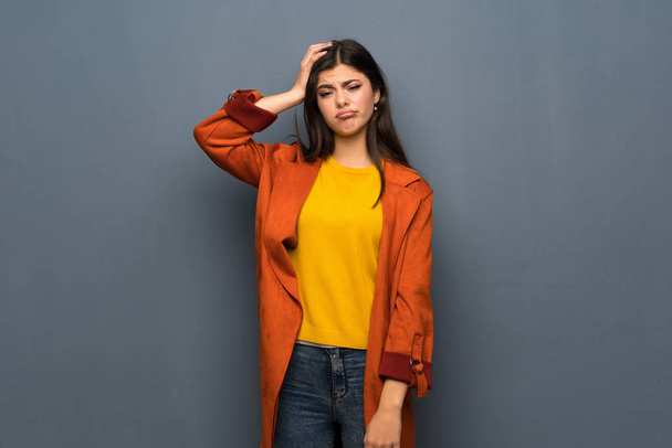 Menina adolescente com casaco sobre a parede cinza com uma expressão de frustração e não compreensão
 - Foto, Imagem