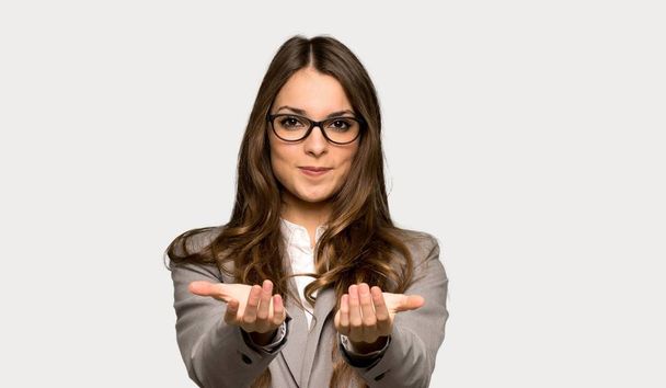 Business woman holding copyspace imaginary on the palm to insert an ad over isolated grey background - Photo, Image