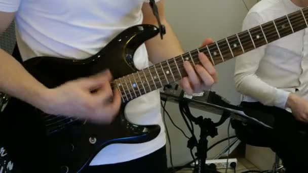 Kädet kitaristi musiikki- tai rock-bändi, joka soittaa sähkökitaraa sisätiloissa
. - Materiaali, video