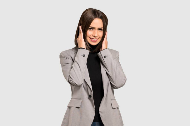 Young business woman frustrated and covering ears with hands on isolated grey background - Photo, Image