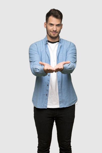 灰色の背景の上に広告を挿入するハンサムな男の手のひらに架空の copyspace を保持 - 写真・画像