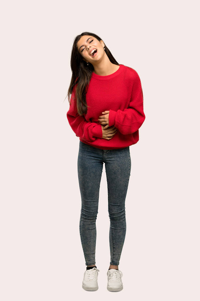 Una toma completa de una adolescente con suéter rojo sonriendo mucho sobre un fondo aislado
 - Foto, Imagen