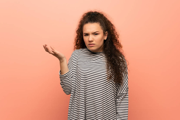 Teenager girl over pink wall making doubts gesture - Фото, зображення