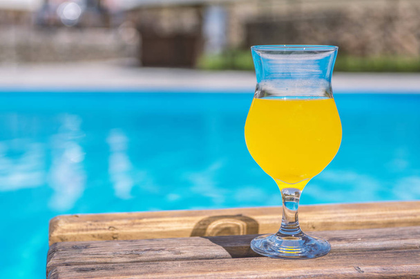 glass of fresh orange or pineapple juice by the poolside - Zdjęcie, obraz