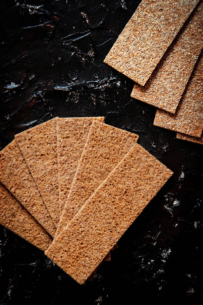Biscoitos crocantes de centeio no fundo da placa preta
 - Foto, Imagem