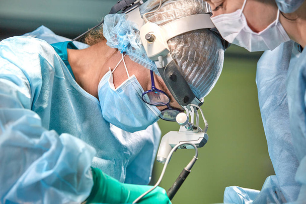 Porträt eines Chirurgen aus nächster Nähe. Chirurgen operieren einen Patienten. Angespannte, ernste Gesichter. Echter Betrieb. Angespannte Atmosphäre im Operationssaal. - Foto, Bild