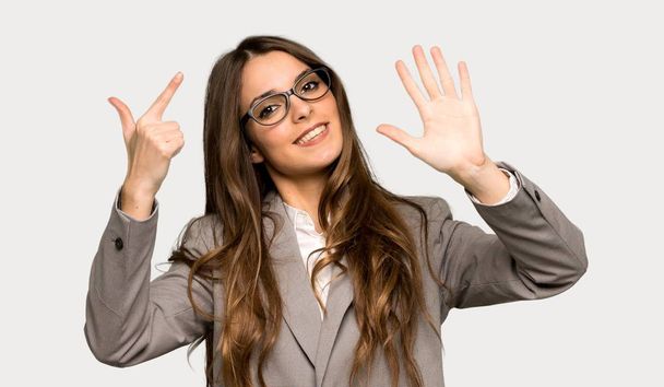Geschäftsfrau zählt sieben mit den Fingern über isoliertem grauen Hintergrund - Foto, Bild