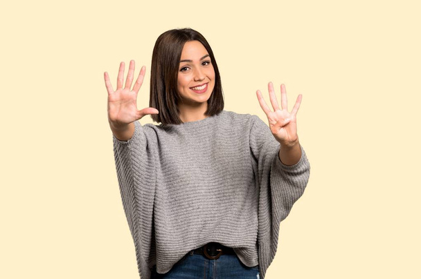 Νεαρή γυναίκα που μετρά εννέα με τα δάχτυλα σε απομονωμένες κίτρινο φόντο - Φωτογραφία, εικόνα