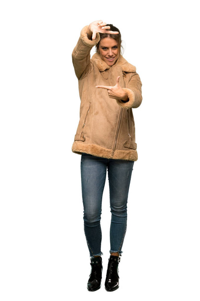 A full-length shot of a Blonde woman with a coat focusing face. Framing symbol over isolated white background - Φωτογραφία, εικόνα