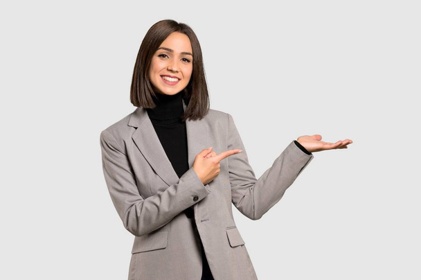Mladá podnikatelka drží imaginární copyspace na dlani vložit inzerát na izolované šedé pozadí - Fotografie, Obrázek