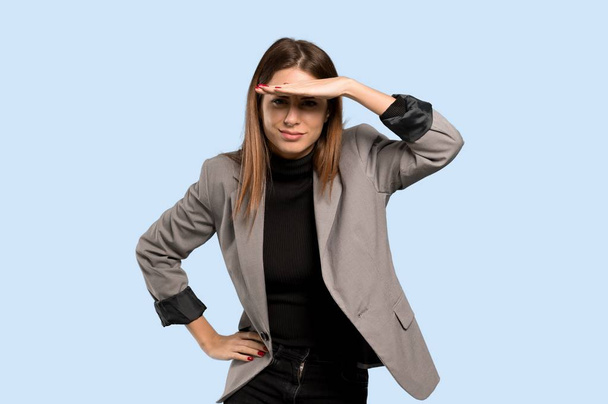 Business woman looking far away with hand to look something over isolated blue background - Photo, Image