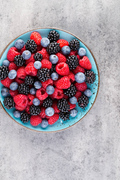 Fresh berry salad on blue dishes. Vintage wooden background. - Photo, Image