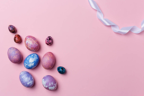 Stylish colorful eggs and quail eggs with white ribbon on pink background, copy space.Happy Easter concept - Foto, afbeelding