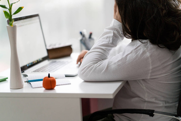 Jonge mannelijke ondernemer werken terwijl zittend op een bureau en die op laptop werkt - Foto, afbeelding