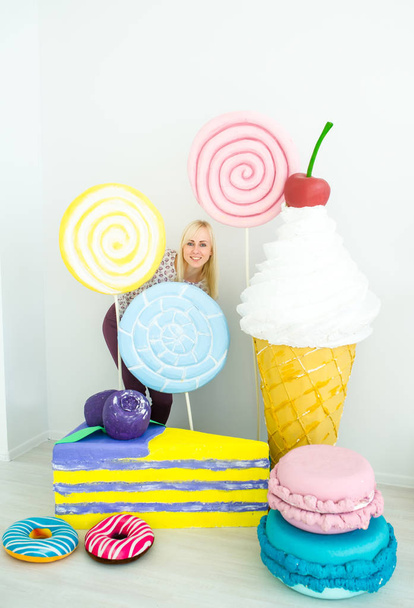 Fun blonde girl posing on decorated background with sweets - Photo, Image