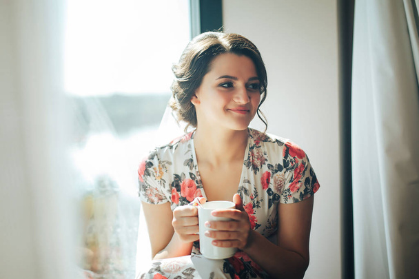 eine schöne junge Braut genießt ihren morgendlichen Kaffee in einem Hotel - Foto, Bild