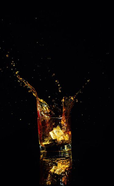 Isolated shot of whiskey with splash on black background - Foto, Imagem