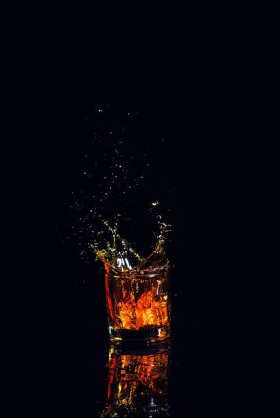 Geïsoleerde shot whisky met splash op zwarte achtergrond - Foto, afbeelding