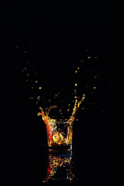 whiskey with splash on black background, brandy in a glass - Fotoğraf, Görsel