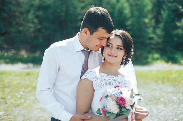 Die glückliche Braut und der Bräutigam stehen im Hintergrund der Natur. Porträt  - Foto, Bild