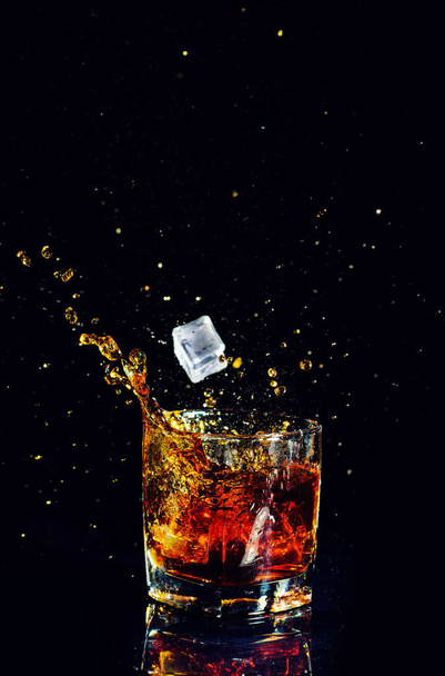 Isolated shot of whiskey with splash on black background - Foto, Imagen