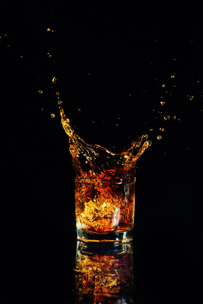 Isolated shot of whiskey with splash on black background - Фото, изображение