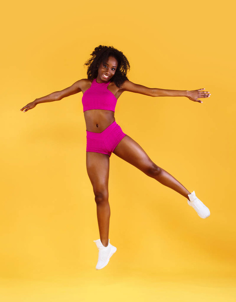 Sporty fit black skin woman, athlete makes fitness exercising on dark background. - Photo, image
