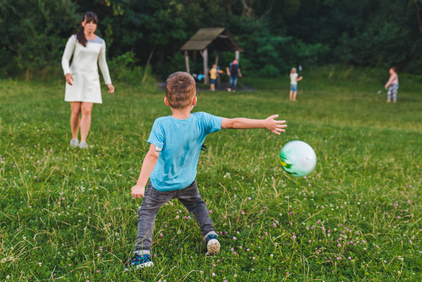 madre jugar con hijo en pelota en el campo verde
. - Foto, imagen