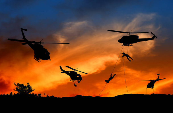 Silhouette Soldiers rappel down to attack from helicopter with sunset - Foto, immagini