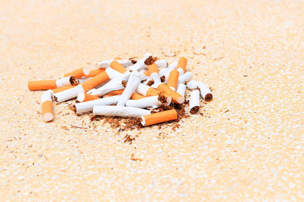 Stapel sigaretten gebroken op tabel terrazzo vloeren gele achtergrond - Foto, afbeelding