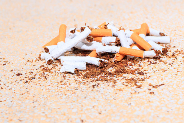 Pilha de cigarros quebrados na mesa piso terrazzo fundo amarelo
 - Foto, Imagem