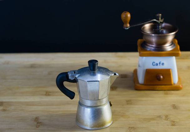 alte italienische Mokka-Kaffeemaschine und manuelle Kaffeemühle im Hintergrund, Holzhintergrund - Foto, Bild