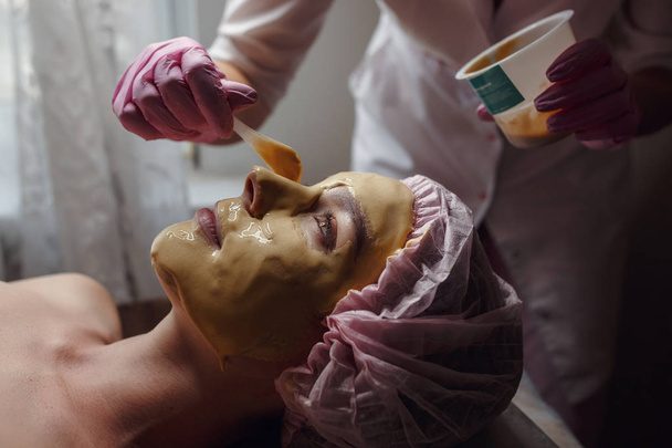 Косметолог робить красу процедури для пацієнта. Пілінг золоту маску - Фото, зображення