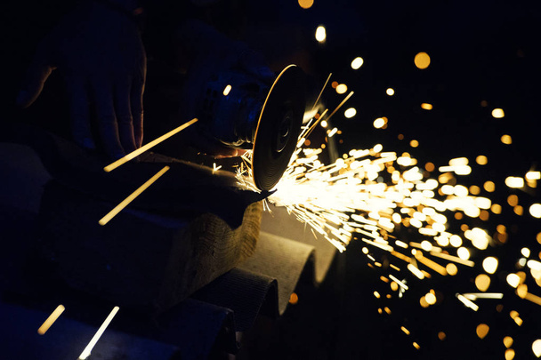 Metal grinding on steel pipe with flash of sparks close up - 写真・画像