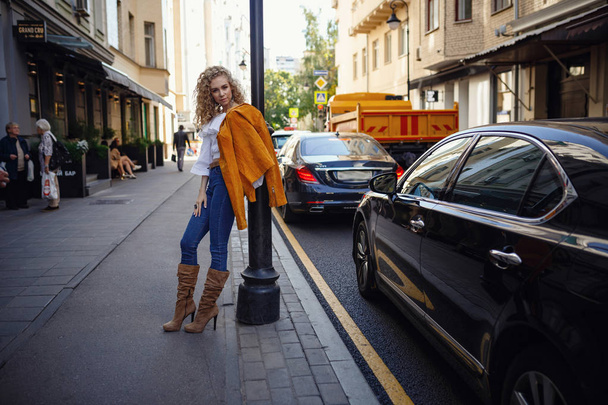 A beautiful young woman with blond curly hair walks through the  - Foto, afbeelding