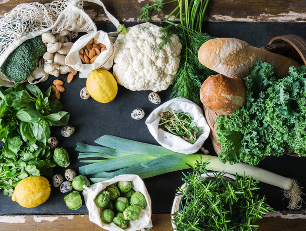 Healthy vegetarian ingredients for cooking. Various clean vegetables, herbs, nut and bread on black background. Products from the market without plastic. Flat lay. - Foto, imagen
